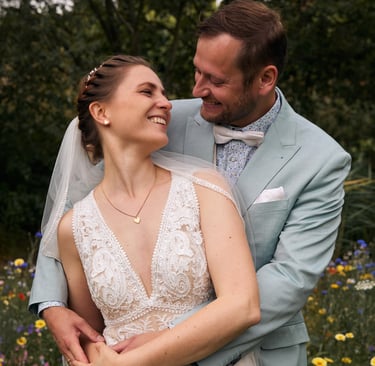 A happy bride and groom embrace in a wildflower garden during their summer wedding ceremony.