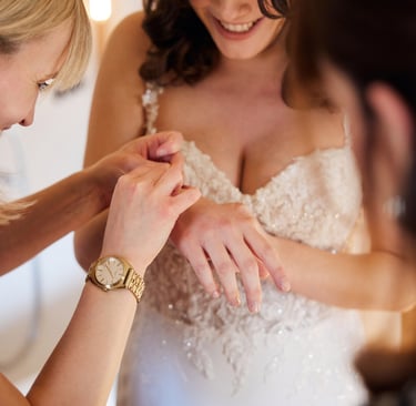 Close-up of a bride and groom's hands with gold wedding bands resting on a floral bouquet.