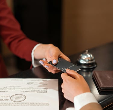 A hotel receptionist handing a black key card to a guest at the check-in desk.