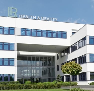 Modern LR Health and Beauty corporate office building with white facade and blue windows.