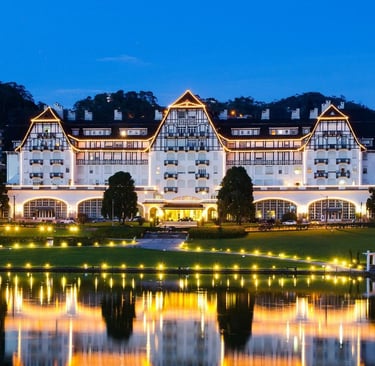 Fachada iluminada do Palácio Quitandinha refletida no lago ao anoitecer em Petrópolis.