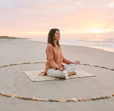 donna seduta su spiaggia in cerchio di conchiglie all'alba