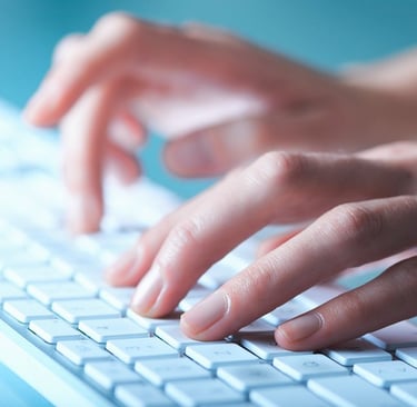 Close-up of hands typing on a modern white computer keyboard for office productivity.