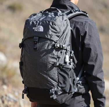 Sturdy backpacks arranged on a wooden bench with mountain peaks in background