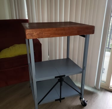 Industrial rolling kitchen cart with a thick wood butcher block top and gray metal storage shelves.