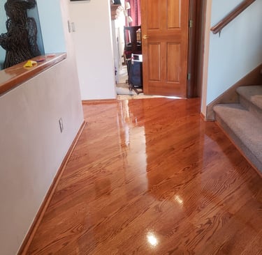 Polished red oak hardwood flooring with a high-gloss finish in a home entryway and hallway.