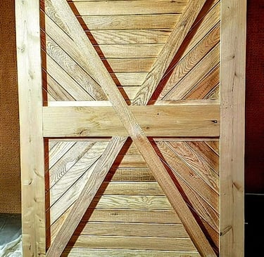 Handcrafted rustic sliding barn door made of light natural wood featuring a geometric X-brace design.