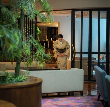 a woman dressed in kimono greeting customers from the lobby of the chaharu hotel