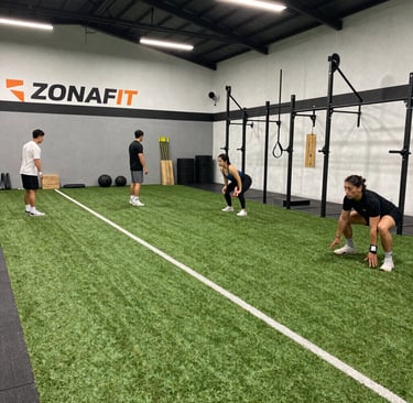 Modern gym area with people using various strength and mobility equipment.