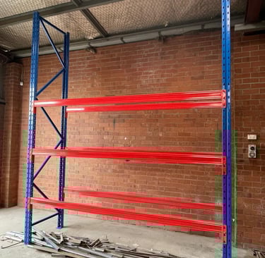Heavy-duty steel pallet racking with assembled uprights and three sturdy shelves.