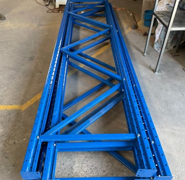 Stack of assembled steel pallet racking uprights neatly arranged.