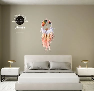 Tree of life dreamcatcher with colorful chakra stones and feathers hanging over a modern bedroom bed.