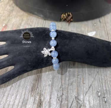 Aquamarine beaded bracelet with a silver flower charm on a black velvet display hand.