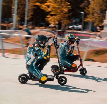 two people riding scooters on a skateboard