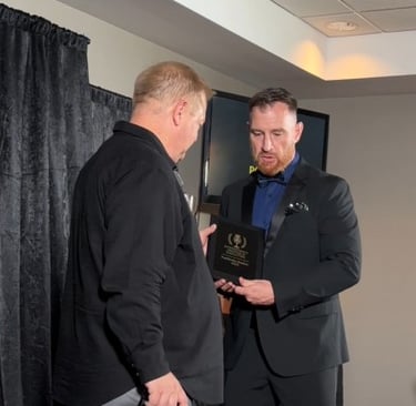 Studio owner, Bill Brassow gets international podcast award from Atlas Aultman on stage