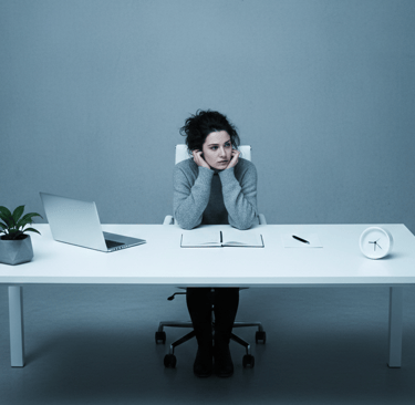 a woman sitting at a desk with a laptop and a clock