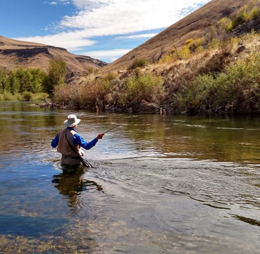 man fishing for trout or bass on a river