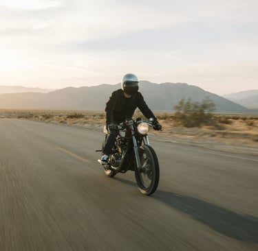 a man riding his cafe racer motorcycle on the road