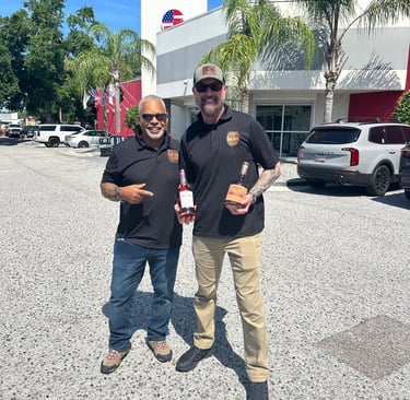 two men wearing bullets and bourbon polos holding two different bottles of bourbon