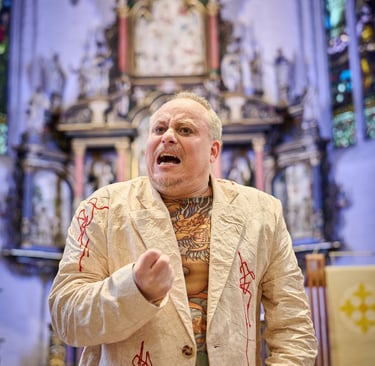 Ein Schauspieler ruft sehr emotional. Hinter ihm ein Kirchenaltar.