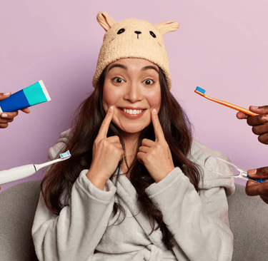 Mujer sonriente rodeada de herramientas de cuidado dental como cepillos de dientes, pasta y limpiado