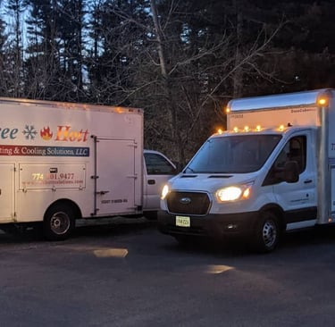 Two Icee Hott Heating & Cooling Solutions service trucks parked at dusk for HVAC maintenance.