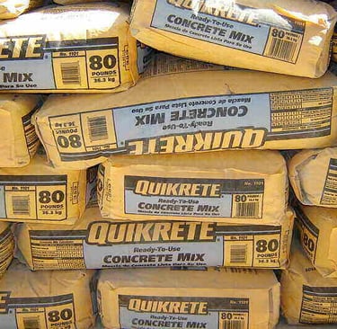 Stacks of 80lb pre-mixed concrete bags ready for a residential post installation project.