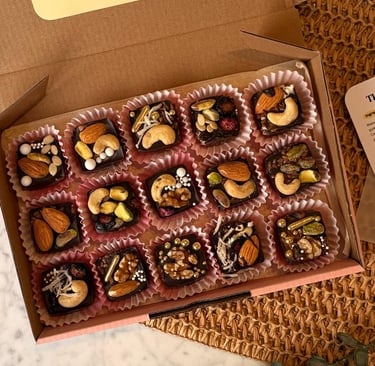 A box of panjeeri bites, chocolate and nuts on top