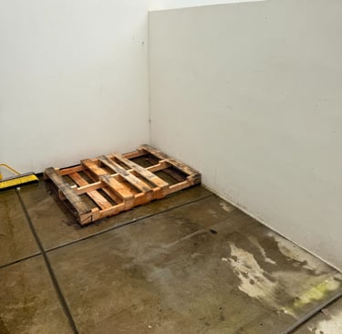 Empty concrete floor with a pallet next to a concrete wall