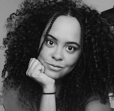 Black and white portrait of a woman with voluminous curly hair and face-framing braids.