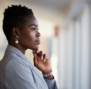 Una mujer afro con pendientes de perla y mirada pensativa