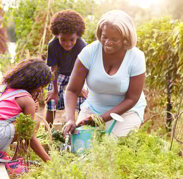 Una mujer afro con dos crios en un jardin