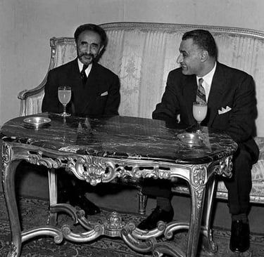 Haile Selassie and Gamal Abdel Nasser meeting in a formal room sitting at a marble table.