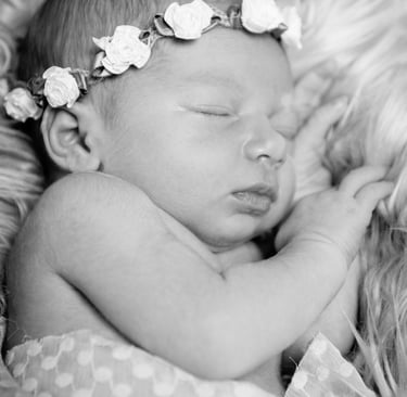 Bébé endormi avec une jolie couronne de fleurs posée sur sa tête, photo en noir et blanc
