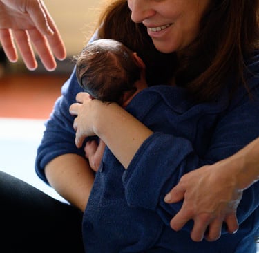 Une maman tenant son nouveau-né dans les bras après le Bain des Merveilles