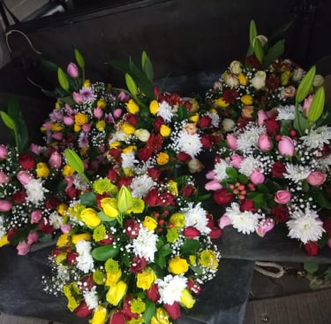 Assorted colorful flower bouquets with roses, lilies, and daisies in a car trunk for delivery.