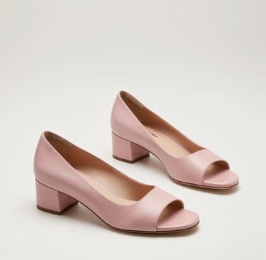 Close-up of a soft gold-toned stiletto heel with delicate shadows.
