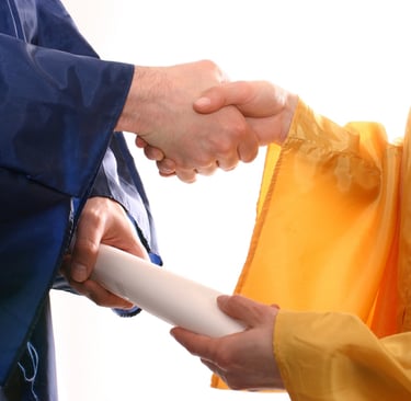 A man and a women shaking hands and holding a diploma