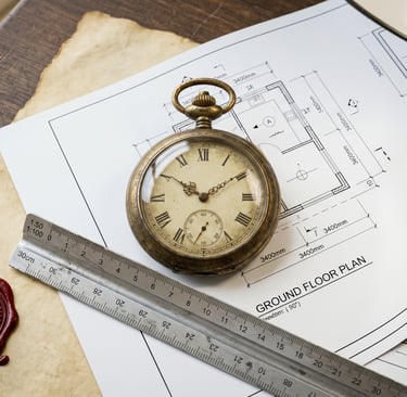 Reloj antiguo sobre planos arquitectónicos modernos representando plazos legales.