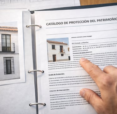 Mesa de consultoría técnica consultando el Catálogo de Protección del Patrimonio para verificar la v
