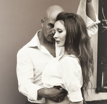 una pareja romántica posando muy cerca, ambos vestidos con elegantes camisas blancas.