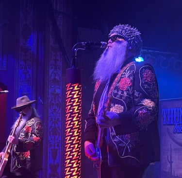 ZZ Top tribute band performing live with long beards and embroidered jackets on stage.