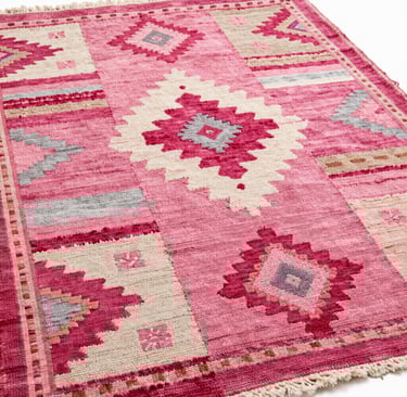 Handwoven Moroccan rug featuring warm sand and terracotta tones, draped over a rustic chair in a cozy corner.