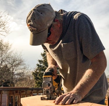 Brewer Construction carpenter using an impact driver on a wooden deck structure in Evergreen.