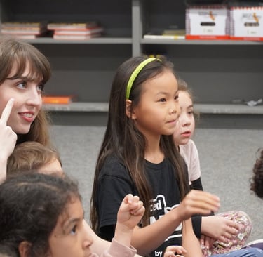 A teacher and diverse elementary students learning sign language in a classroom setting.