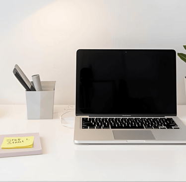 a laptop computer sitting on a desk with a lamp