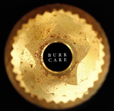 Top-down view of a coffee grinder conical burr with grounds on a black background.