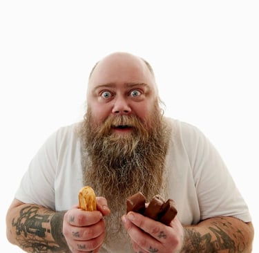 Homme barbu tenant des barres chocolatées dans les mains, regard intense face à l’objectif.