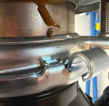 Close-up of a metal garbage disposal mounting assembly showing a secure locking ring under a kitchen sink.