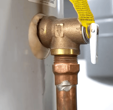 Close-up of a brass temperature and pressure relief valve installed on a residential water heater tank.